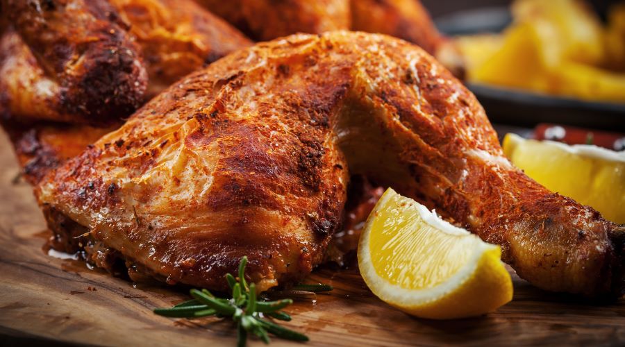 Gegrillte Zitronen-Hähnchenschenkel mit knuspriger Haut, serviert mit frischem Rosmarin und Zitronenspalten – perfektes Frühlingsgericht vom Grill.