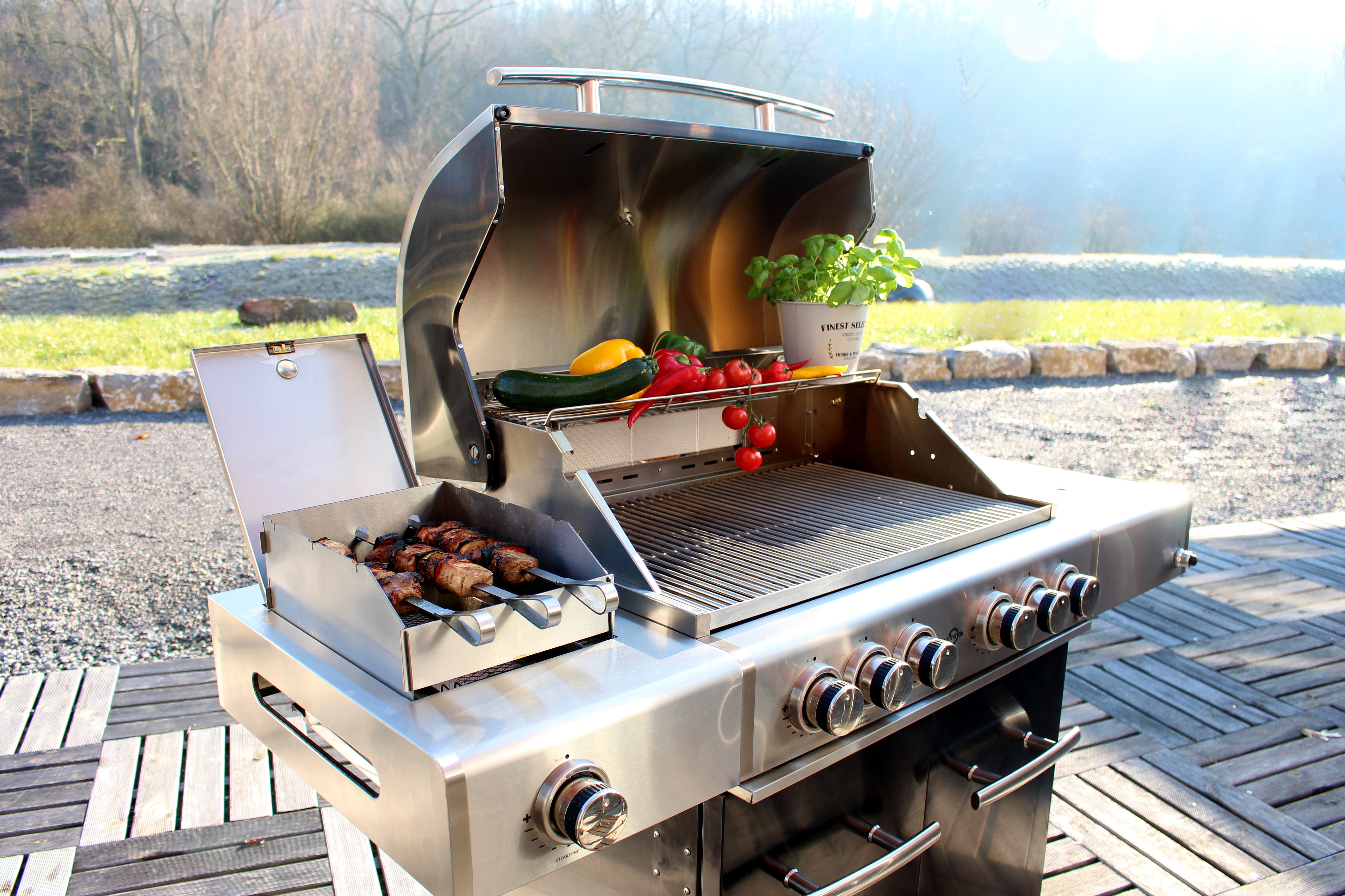 Ein Foto eines neuen luxuriösen Gasgrills mit dekorativem Gemüse und Fleischspießen zur Ausstellung