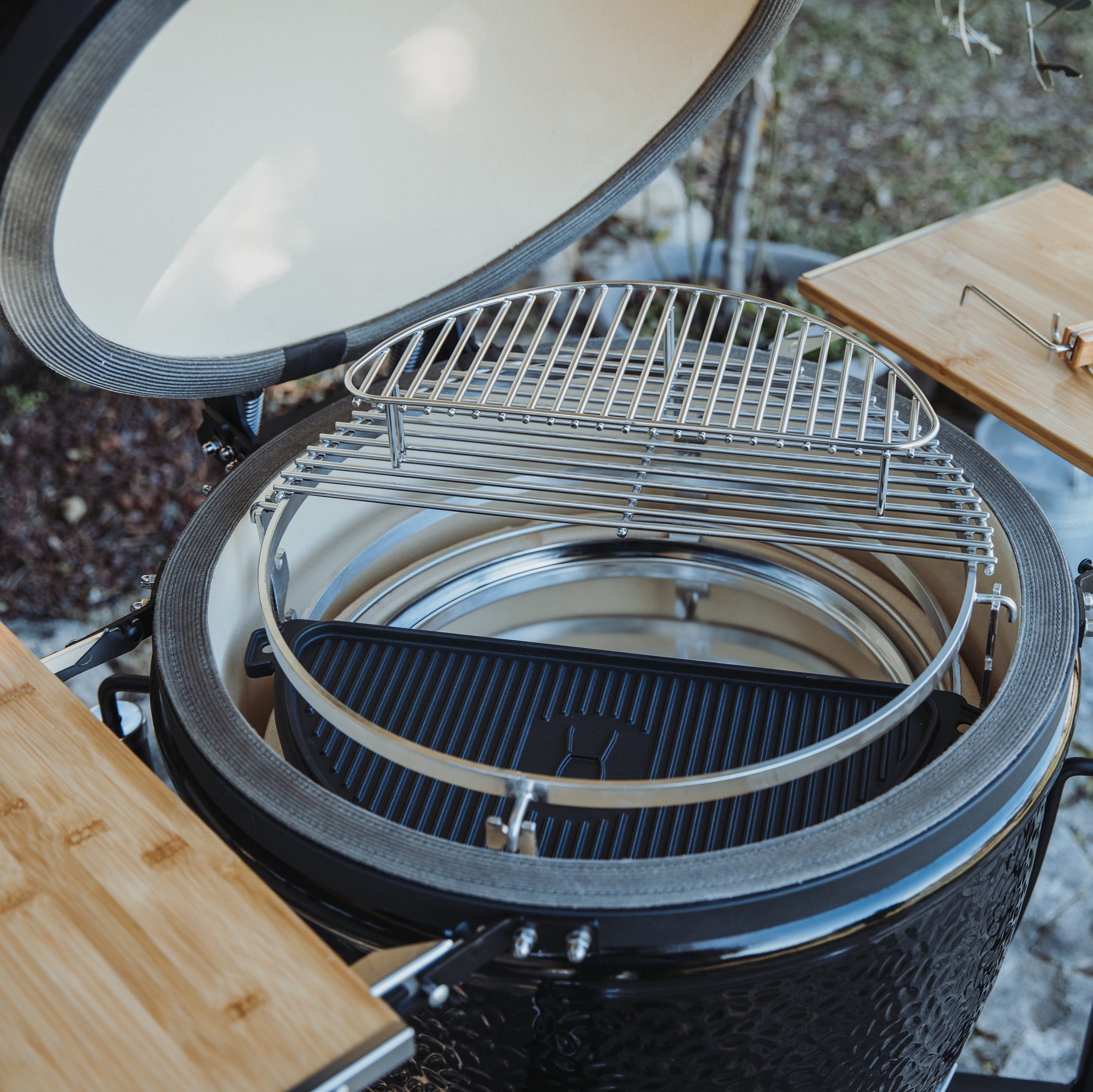 Detailansicht des geöffneten MONOLITH ONE.55 Kamado-Grills mit Smart Grid System, Gusseisen-Grillplatte und Edelstahl-Zusatzrost – flexible Grillzonen für vielseitiges Outdoor-Cooking.