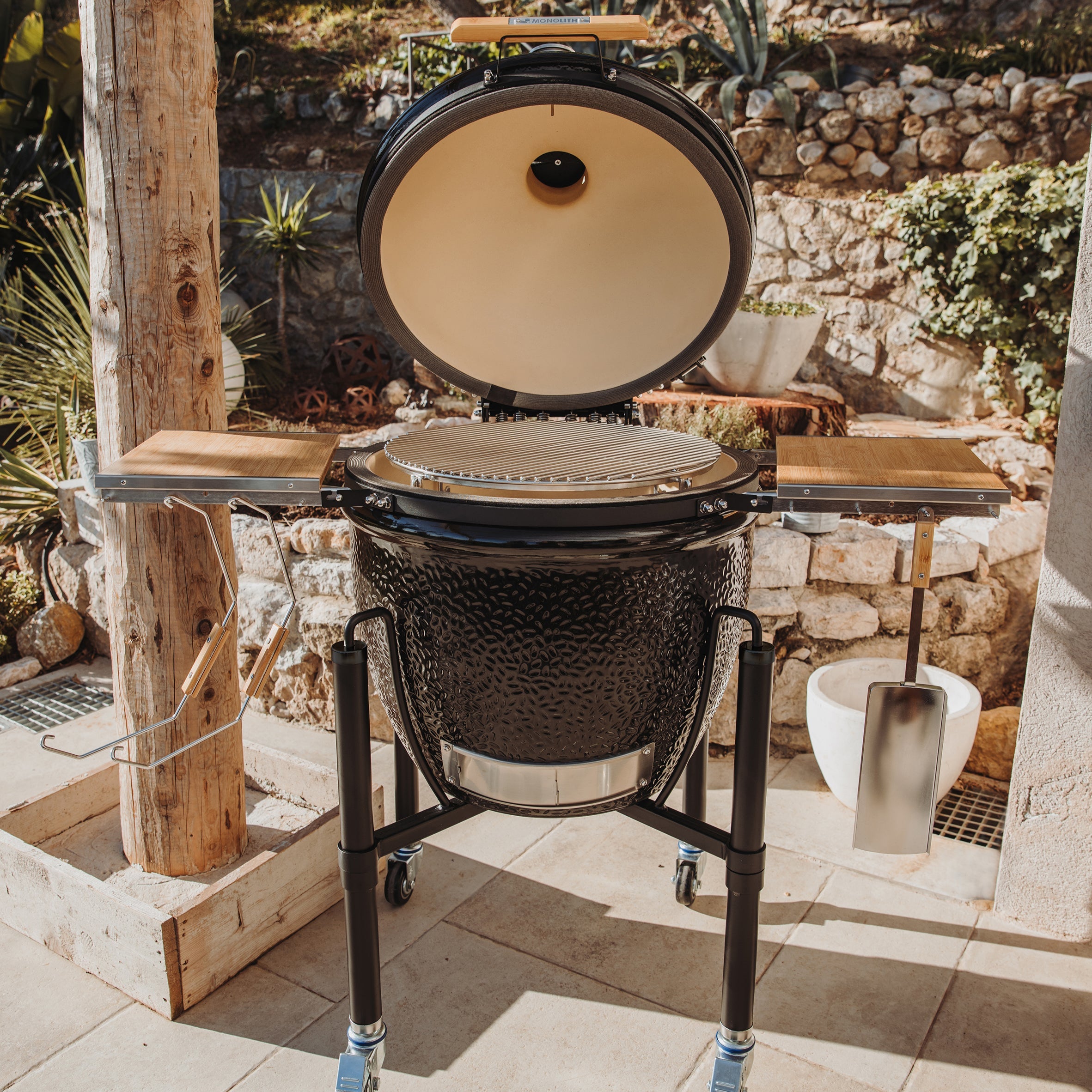MONOLITH ONE.66 Kamado-Grill geöffnet mit Edelstahlrosten und Bambus-Seitentischen – Outdoor-Grill mit großer Grillfläche in Aktion.