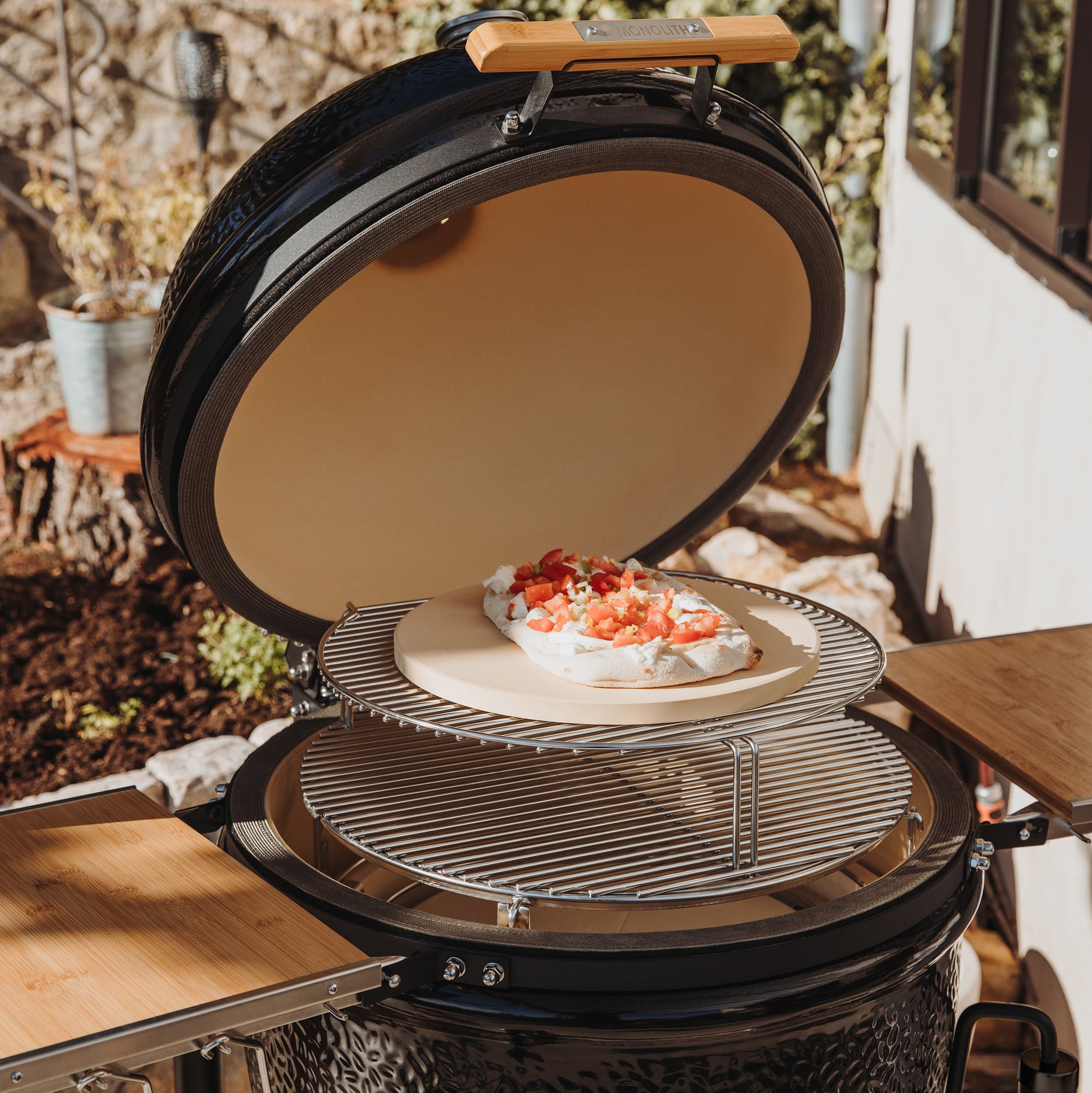 MONOLITH ONE.66 Kamado mit geöffnetem Deckel und Pinsa auf Pizzastein – BBQ-Grill mit Zusatzrost für kreatives Backen im Freien.