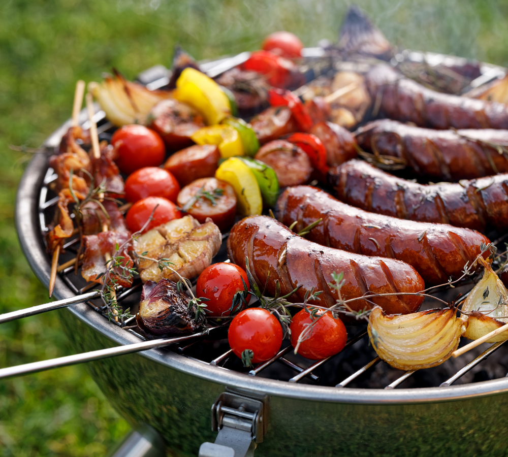 Vielfältig belegter Holzkohle Grill mit diversem Grillgemüse, Würstchen und Spießen