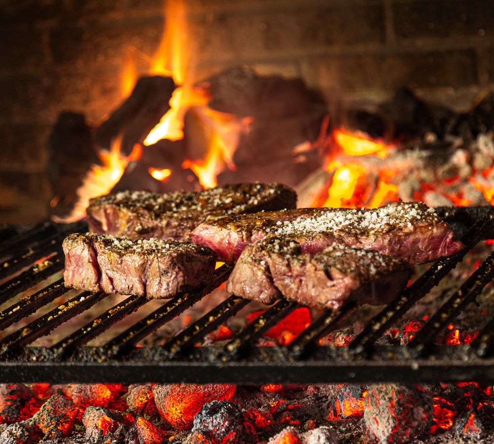 Steak auf Gusseisenrost im Steinofen auf Holzkohlen