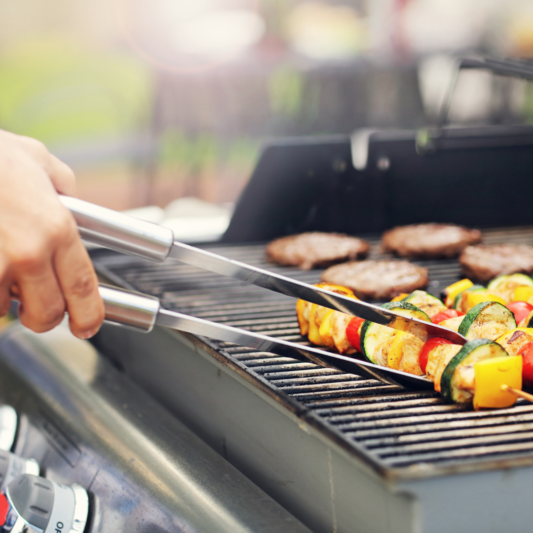 Kompakter Grill auf einem kleinen Balkon mit frischem Gemüse und Fleischspießen, perfekt für das Grillen auf begrenztem Raum.